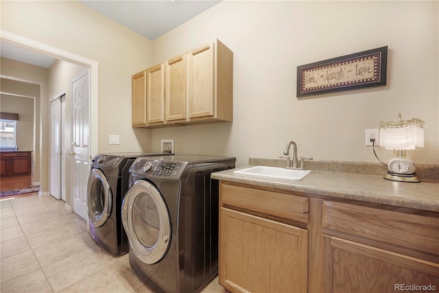 clothes washing area featuring separate washer and dryer, sink, light tile patterned floors, and cabinets