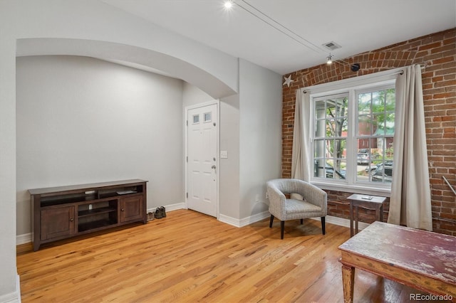 1580 N Franklin St, Denver, CO 80218 - living area featuring arched walkways, light wood-style flooring, brick wall, and baseboards
