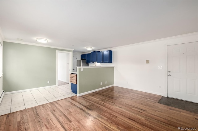 unfurnished living room with crown molding, baseboards, and wood finished floors