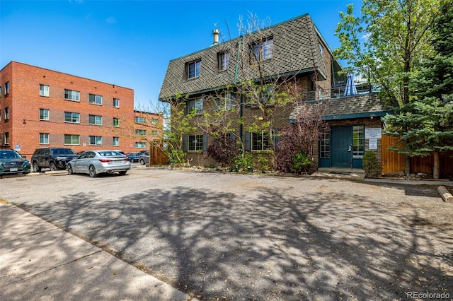 exterior space with mansard roof and uncovered parking