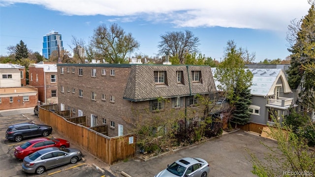 view of building exterior with fence and uncovered parking