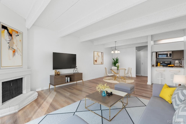 living room with beam ceiling, light hardwood / wood-style floors, and an inviting chandelier