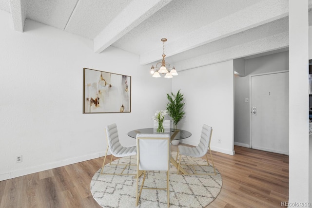 dining area with beam ceiling, wood-type flooring, a textured ceiling, and an inviting chandelier