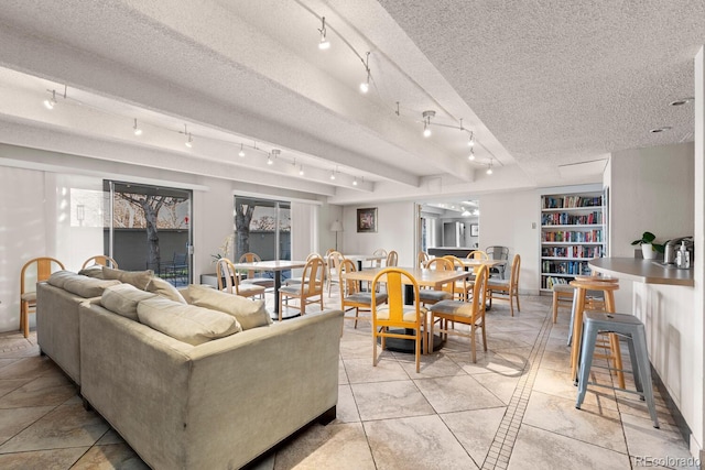 tiled living room featuring rail lighting and a textured ceiling