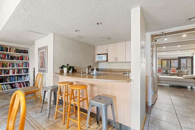 kitchen with a kitchen breakfast bar, kitchen peninsula, and a textured ceiling