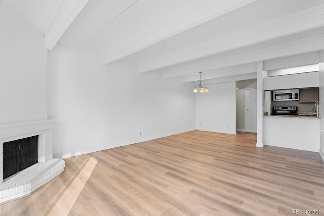 unfurnished living room featuring beamed ceiling, light wood-type flooring, and an inviting chandelier