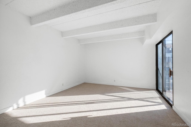 unfurnished room with beamed ceiling, carpet floors, and a textured ceiling