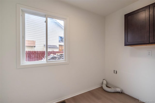 washroom featuring plenty of natural light, cabinets, hardwood / wood-style flooring, and electric dryer hookup