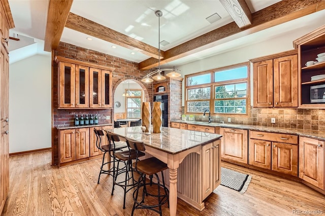 kitchen with beamed ceiling, light wood finished floors, and backsplash