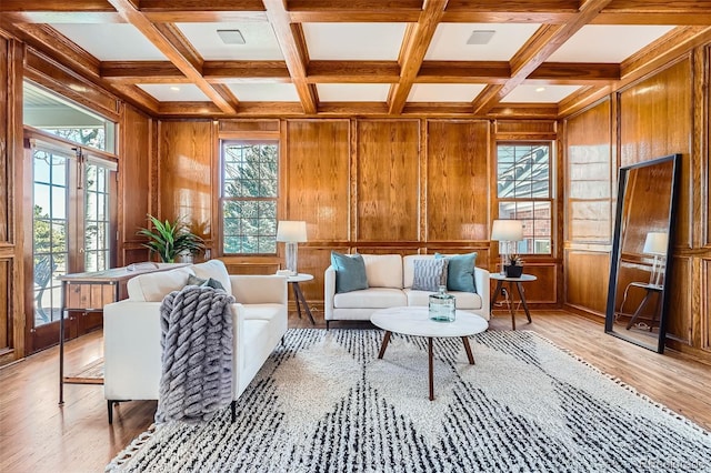 living area featuring beamed ceiling, coffered ceiling, wooden walls, and light wood finished floors