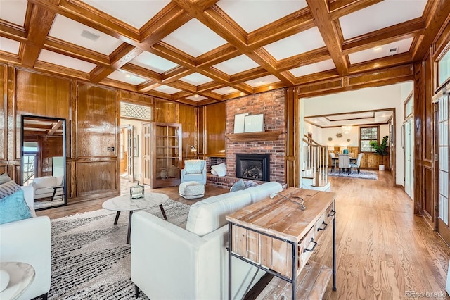 living room with light wood finished floors, wooden walls, and coffered ceiling