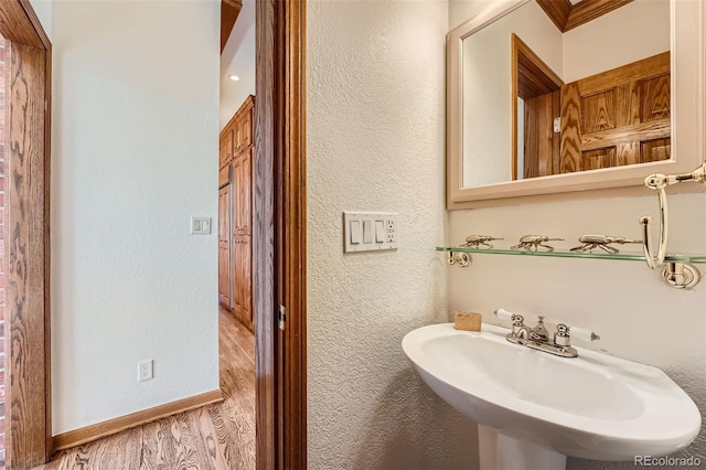 bathroom featuring a sink, baseboards, wood finished floors, and a textured wall