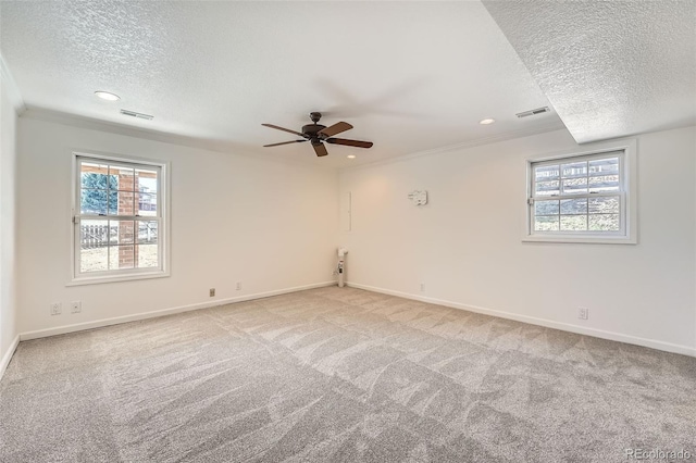 carpeted empty room featuring a wealth of natural light, visible vents, and a ceiling fan