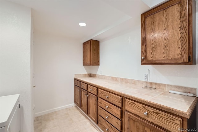 kitchen with recessed lighting, baseboards, brown cabinets, and tile counters