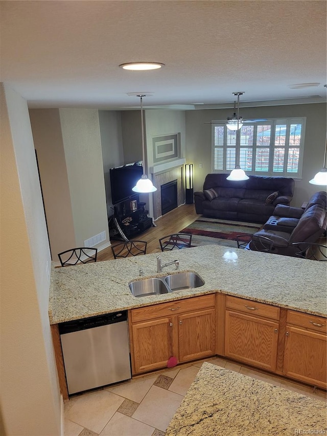 kitchen with light stone countertops, sink, stainless steel dishwasher, and decorative light fixtures