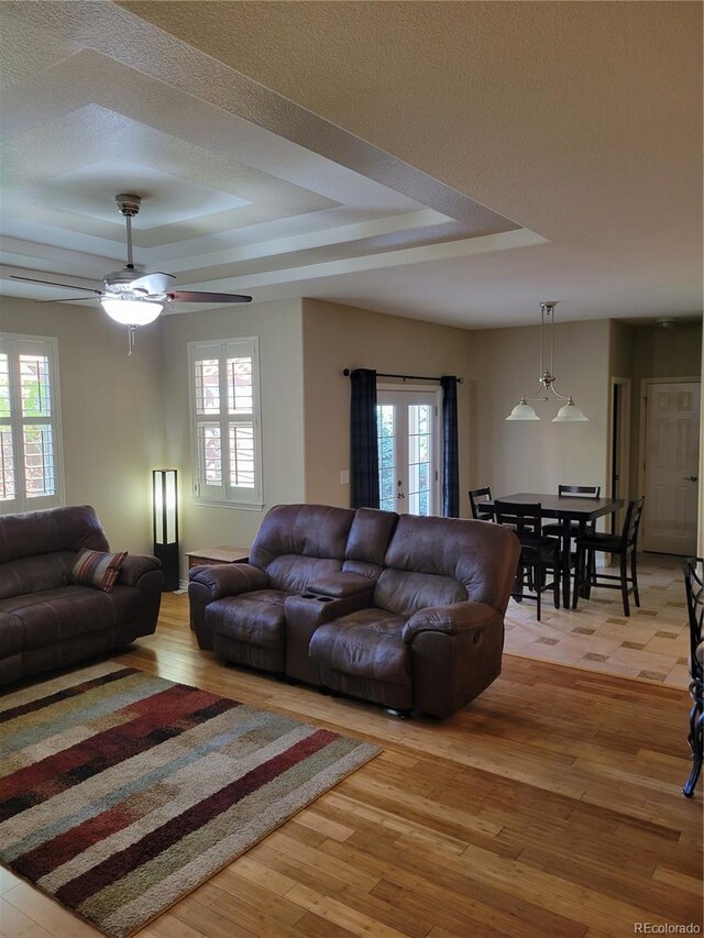 living room featuring a tray ceiling, light hardwood / wood-style floors, and a textured ceiling