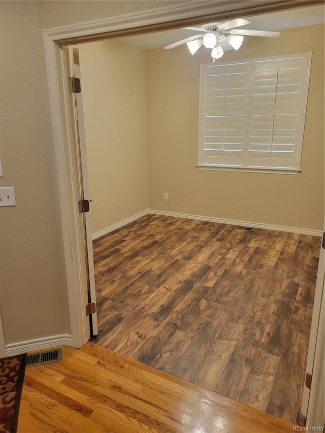 empty room featuring dark wood-type flooring and ceiling fan