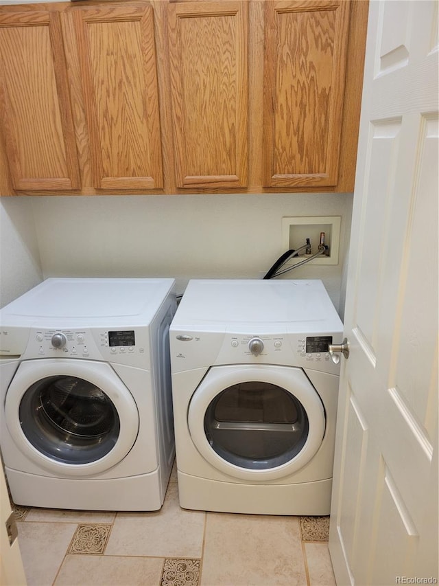 washroom with cabinets, light tile patterned flooring, and washer and clothes dryer