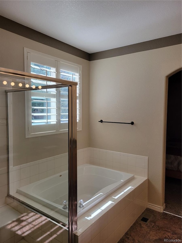 bathroom featuring tiled tub and a textured ceiling