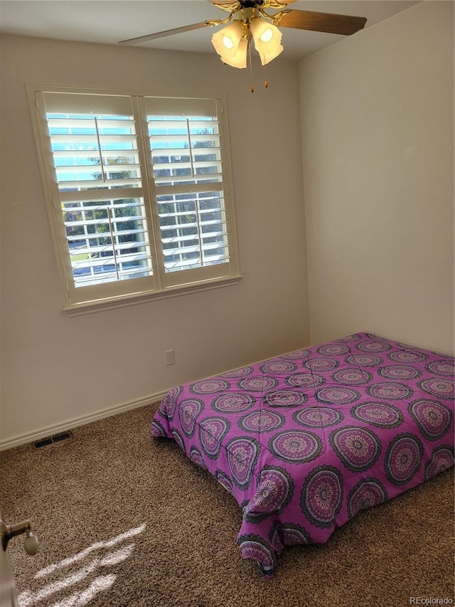 carpeted bedroom featuring multiple windows and ceiling fan