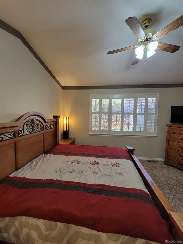 carpeted bedroom with multiple windows, vaulted ceiling, ornamental molding, and ceiling fan