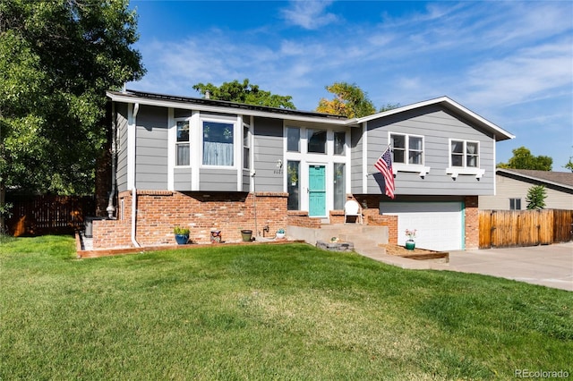 bi-level home with concrete driveway, an attached garage, brick siding, and fence