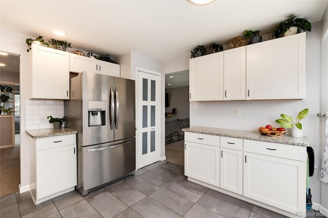 kitchen featuring decorative backsplash, white cabinetry, light tile patterned floors, and stainless steel fridge with ice dispenser