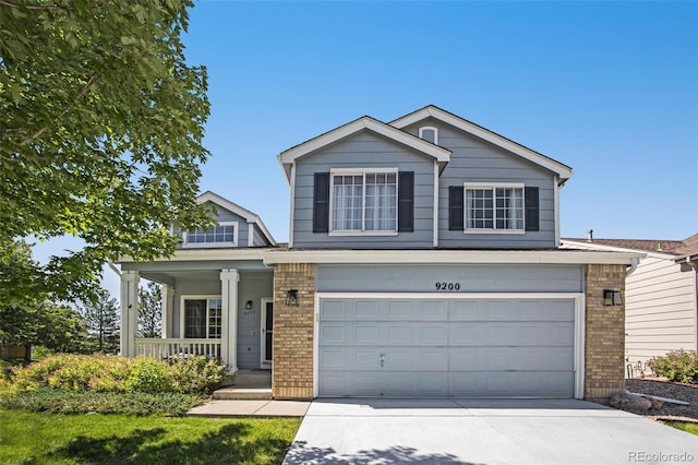 9200 W Indore Dr, Littleton, CO 80128 - traditional home featuring a porch, brick siding, a garage, and driveway