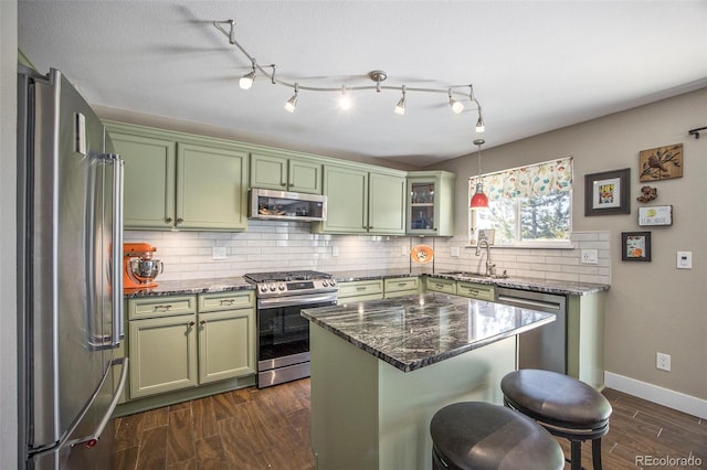 9200 W Indore Dr, Littleton, CO 80128 - kitchen with green cabinetry, stainless steel appliances, a kitchen bar, and decorative backsplash