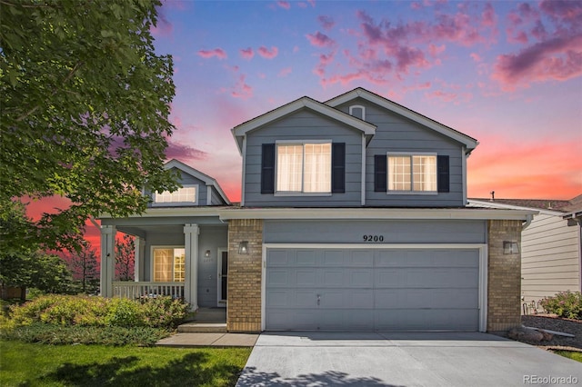 9200 W Indore Dr, Littleton, CO 80128 - traditional-style home with covered porch, brick siding, a garage, and concrete driveway