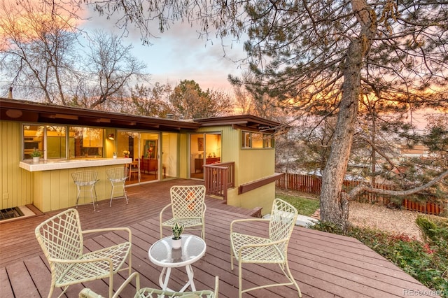 deck at dusk featuring a bar