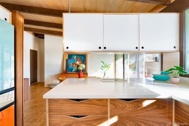 kitchen featuring vaulted ceiling with beams, white cabinetry, and wood ceiling