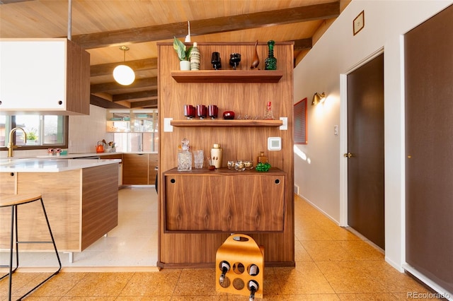 kitchen with wood ceiling, lofted ceiling with beams, decorative light fixtures, and a kitchen breakfast bar