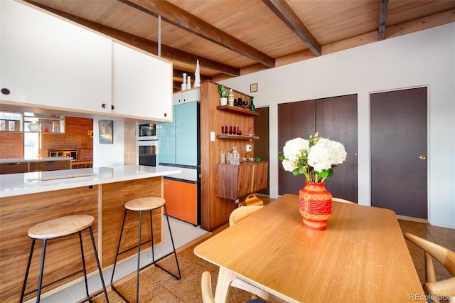 kitchen with beam ceiling, wooden ceiling, kitchen peninsula, white cabinets, and appliances with stainless steel finishes