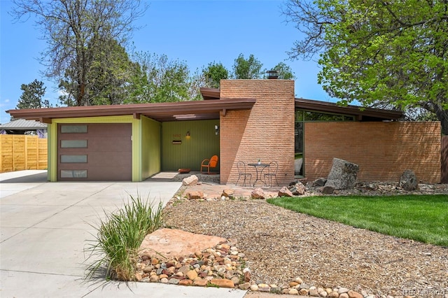 5450 Mohawk Rd, Littleton, CO 80123 - view of front facade with driveway, an attached garage, fence, and a chimney