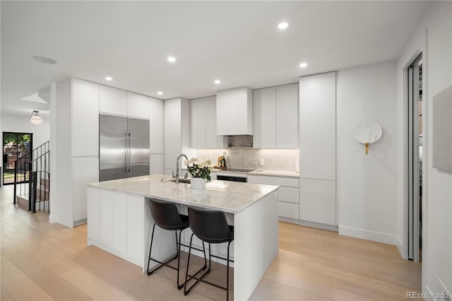 332 S Franklin St, Denver, CO 80209 - kitchen with stainless steel built in refrigerator, light wood-style flooring, backsplash, a breakfast bar area, and recessed lighting