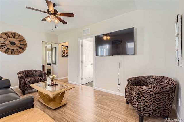 living room featuring light hardwood / wood-style floors, vaulted ceiling, and ceiling fan