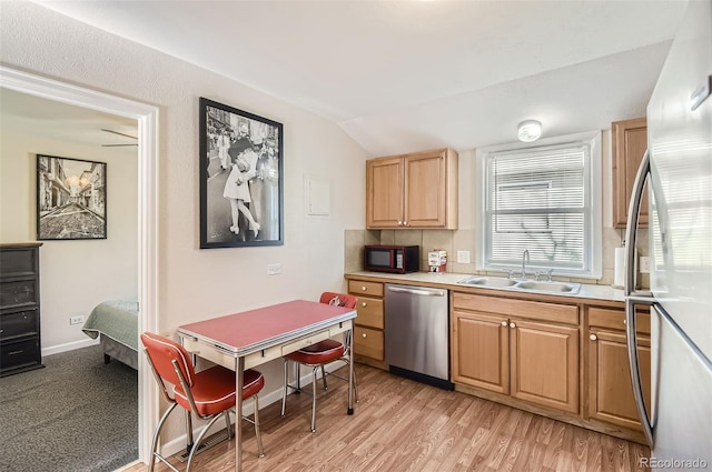 kitchen with lofted ceiling, sink, stainless steel appliances, and light wood-type flooring