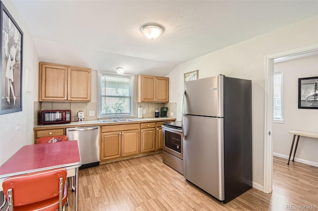 kitchen with light hardwood / wood-style flooring, stainless steel appliances, vaulted ceiling, and sink