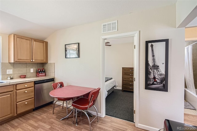 kitchen featuring lofted ceiling, light brown cabinets, tasteful backsplash, stainless steel dishwasher, and light hardwood / wood-style floors