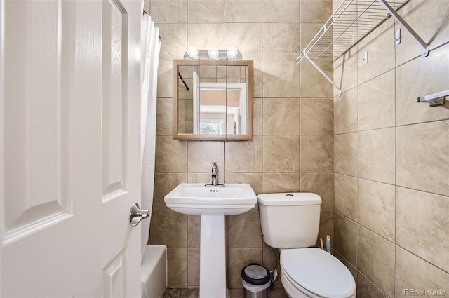 bathroom featuring toilet, shower / bath combo, and tile walls