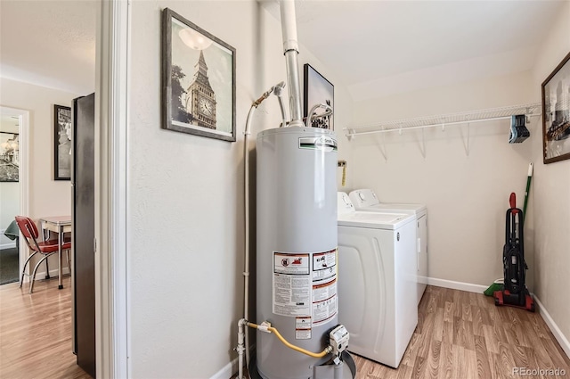 clothes washing area featuring water heater, separate washer and dryer, and light wood-type flooring