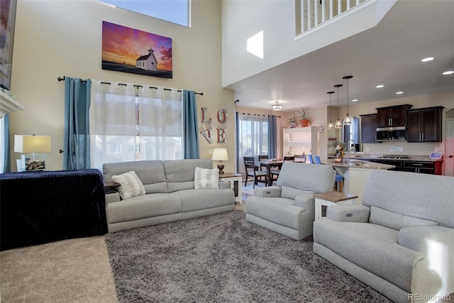 carpeted living room featuring a towering ceiling