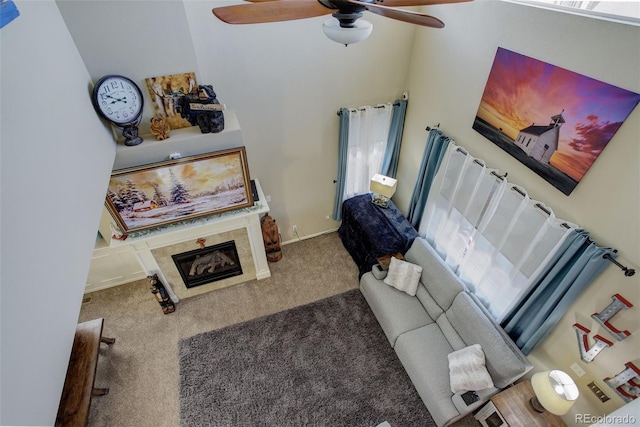 carpeted living room with ceiling fan and a fireplace