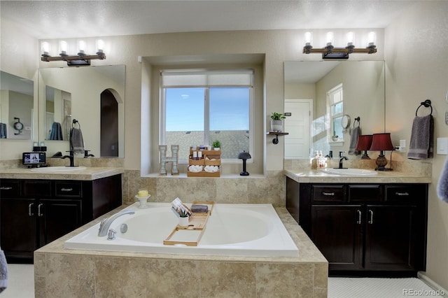 bathroom with vanity and tiled tub