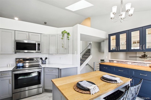 kitchen featuring vaulted ceiling with skylight, glass insert cabinets, stainless steel appliances, and butcher block counters