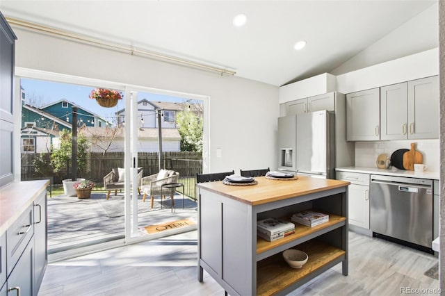 kitchen with stainless steel dishwasher, open shelves, fridge with ice dispenser, vaulted ceiling, and gray cabinetry