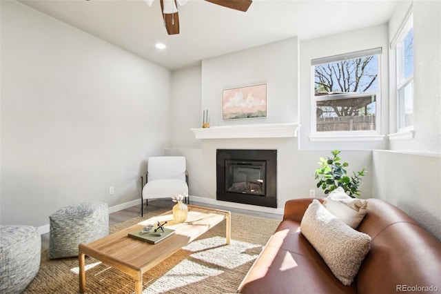 living room with ceiling fan, wood finished floors, baseboards, a glass covered fireplace, and recessed lighting