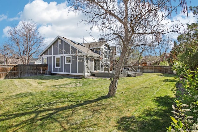 back of property with a fenced backyard, a yard, and a chimney