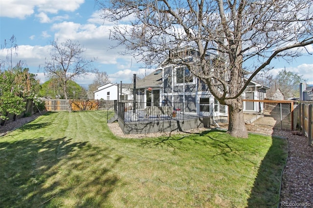 rear view of property featuring a lawn and a fenced backyard